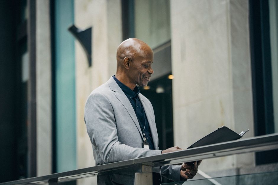 A person in professional business attire sits at a desk in a bright, modern office, carefully reviewing the legal details of a contract.